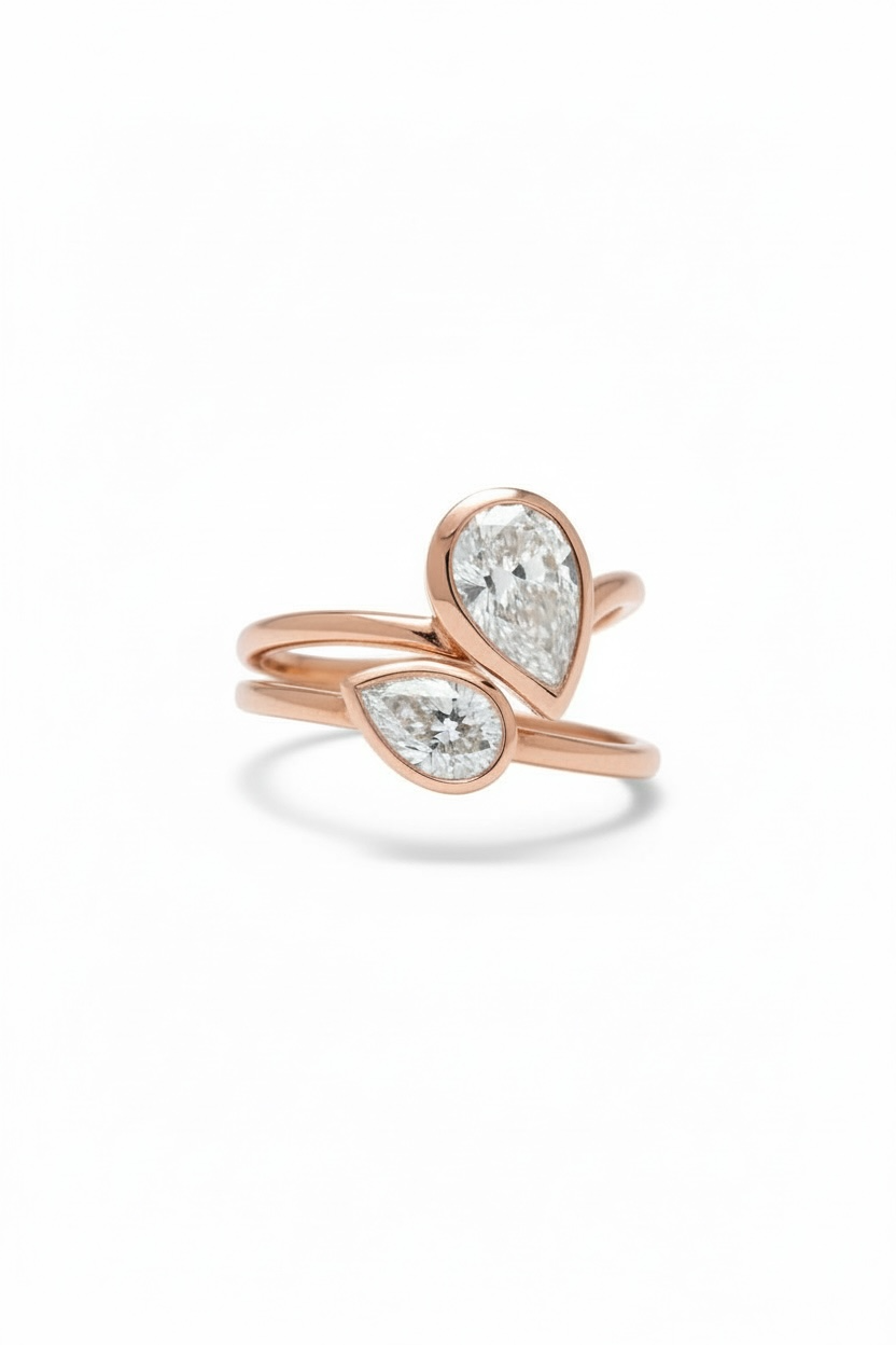 Rose gold rings with pear-shaped diamond on a white background