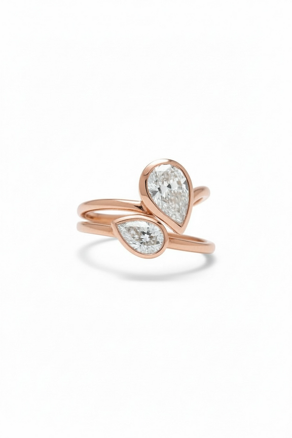 Rose gold rings with pear-shaped diamond on a white background