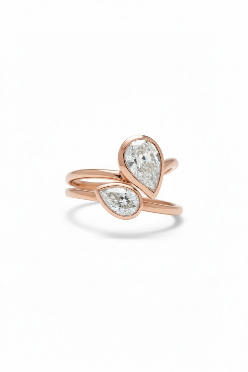 Rose gold rings with pear-shaped diamond on a white background