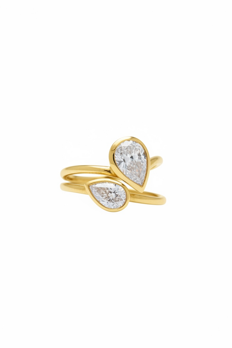 Gold ring with teardrop-shaped diamond on a white background