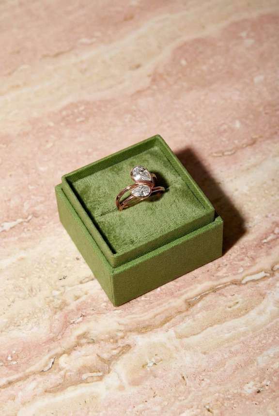 Gold ring with a diamond in a green velvet box on a marble surface