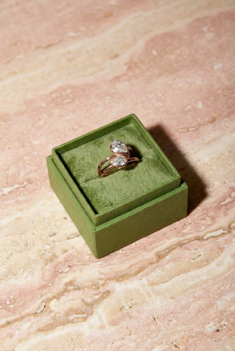 Gold ring with a diamond in a green velvet box on a marble surface