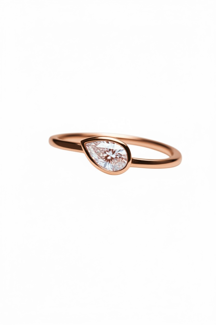 Rose gold ring with a teardrop-shaped diamond on a white background