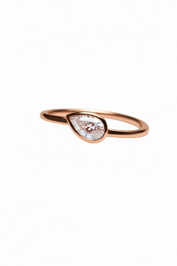 Rose gold ring with a teardrop-shaped diamond on a white background