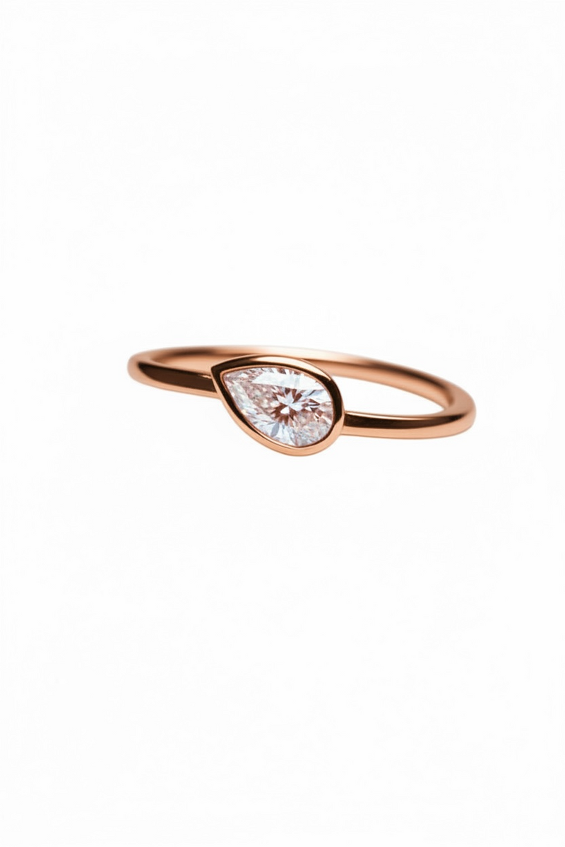 Rose gold ring with a teardrop-shaped diamond on a white background