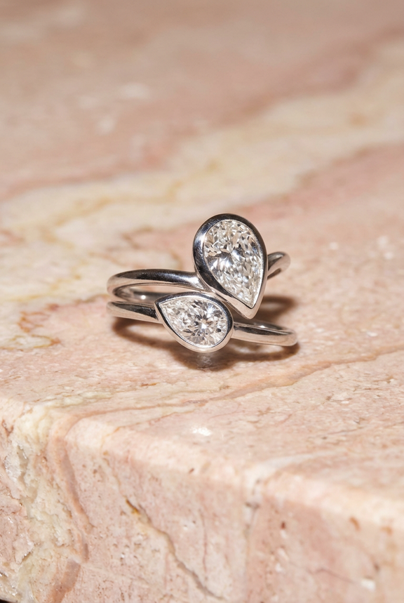  gold ring with teardrop-shaped gemstones on a textured beige surface