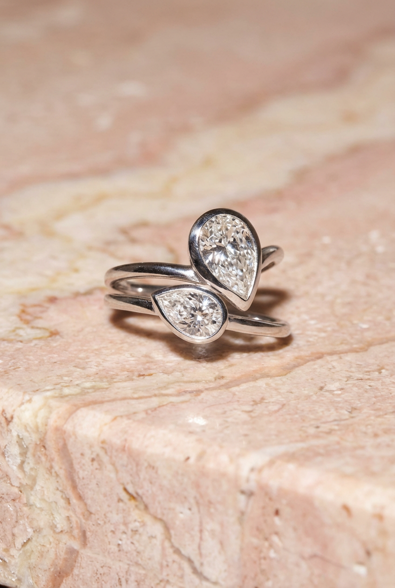 pear shape ring white gold with teardrop-shaped gemstones on a textured beige surface