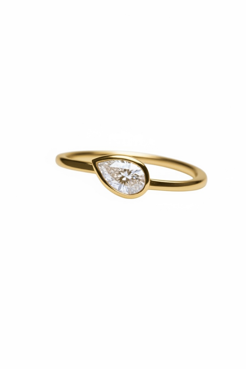 Gold ring with a teardrop-shaped diamond on a white background